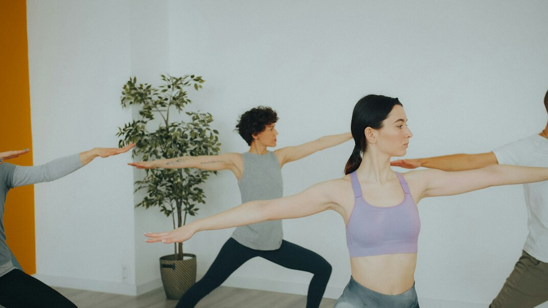 Group fitness class following an instructor in a bright studio